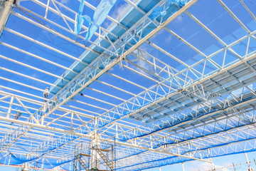 Structure of steel roof frame for building construction on blue sky background.