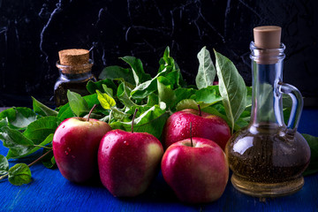 Apple cider vinegar. Three glass bottle on blue background. Red apples.