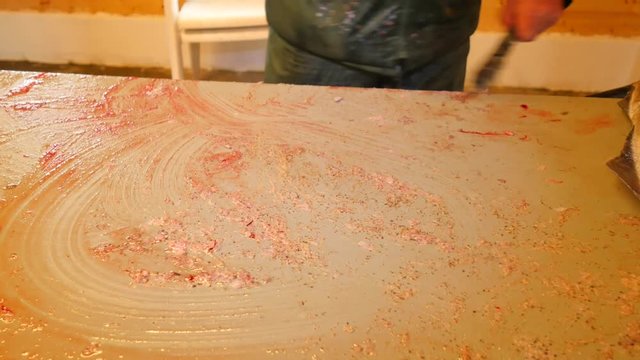 Cod, the coalfish. Quick removing of scales with a wire brush on a filing table. View of strong male hands working with sea fish. Removed scales and blood on the table.
