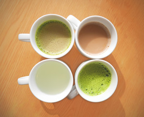 Four cups of hot drinks on wood table in muted mode