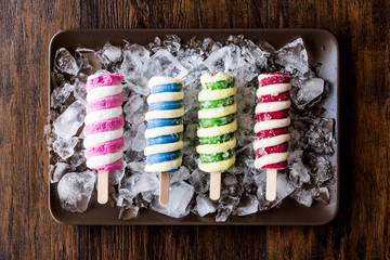 Popsicles ice cream with ice on dark surface.
