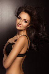 Fototapeta premium Brunette sexy woman posing in black lingerie, looking at camera.