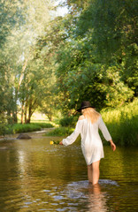 Young woman in the white dress in the middle of a creek..