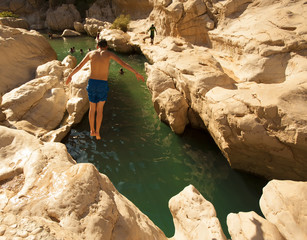 Man jumping in a mountain lake. The beautiful mountain scenery. Wadi Bani Khalid. Oman.