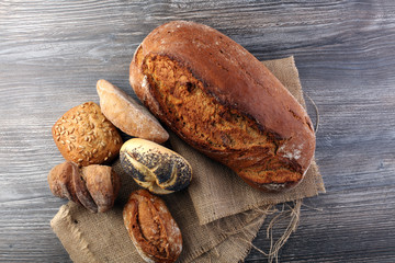 Different kinds of bread and bread rolls on board from above. Kitchen or bakery poster design.