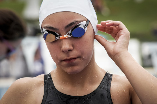 Chica practicando el deporte de la natación en piscina de verano antes de saltar a su prueba