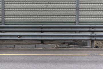 Gray metal sheet fence with concrete sidewalk and asphalt road