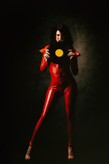 Jeune femme sexy en combinaison latex rouge,un disque vinyle dans les mains