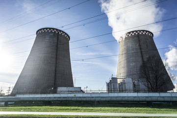 Two cooling towers emitting steam, with a blue sky background