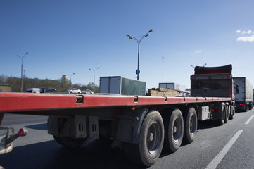 Large powerful big rig semi truck with a trailer for transportation of oversized heavy cargo and objects. Trailer with a step down for the transport of high loads. Semi truck drive on green highway