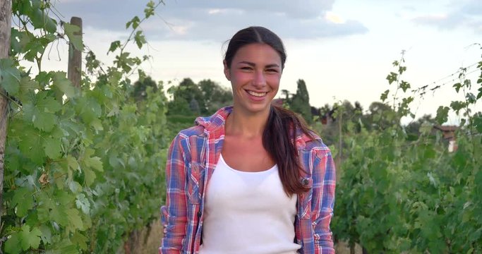 Beautiful girl (woman) farmer smiling watching the grape fields, in a white tank top, in a shirt, greens background Concept ecology, wine, bio product, inspection, water, natural products, agriculture