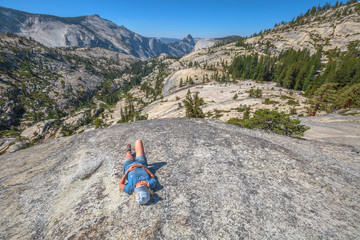 Hiking woman relaxing alone sleeping at Olmsted Point. Tired hiker resting lying down outdoors taking a break from hiking. Young caucasian woman in Yosemite National Park, California, United States.