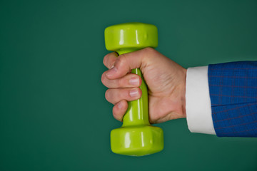 dumbbell in hand of businessman or man on green background