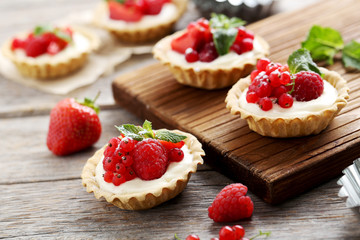 Dessert tartlets with berries on grey wooden background