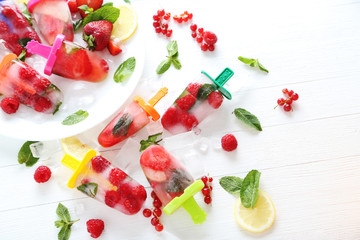 Popsicles with berries on white wooden table