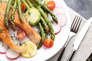 Steak of salmon with asparagus, vegetables, fork and knife