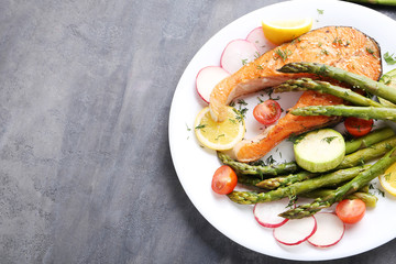 Steak of salmon with asparagus and vegetables on grey wooden table