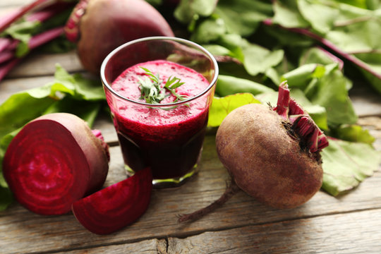 Fresh beets juice in glass on a grey wooden table