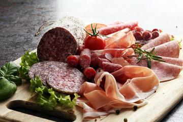 Food tray with delicious salami, pieces of sliced ham, sausage, tomatoes, salad and vegetable - Meat platter with selection