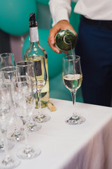 waiter pours wine into the glasses at the buffet table