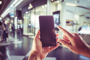 Close-up image of male hands using smartphone. Blurred background on city shopping,  searching or social networks concept