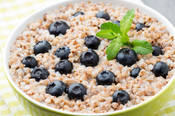 Buckwheat porridge in a bowl with mint leaves and blueberries.