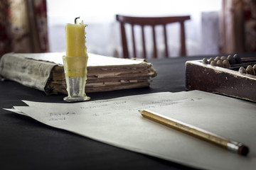 Abacus with candle, book and balance sheet on dark background