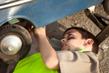 Young boy changing a tire on an old toy car © V&P Photo Studio