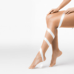 Women's legs with white ribbon
