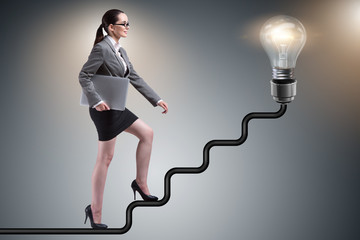 Businesswoman climbing career ladder towards light bulb