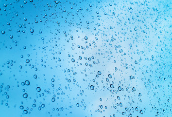 Drops of heavy rain on glass with clearly sky background