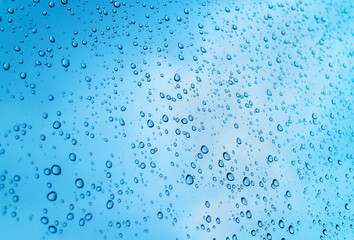 Fototapeta na wymiar Drops of heavy rain on glass with clearly sky background
