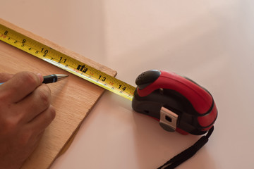 Man draws design, geometric shapes by pencil on wooden boards, wish Ruler and measuring tape.