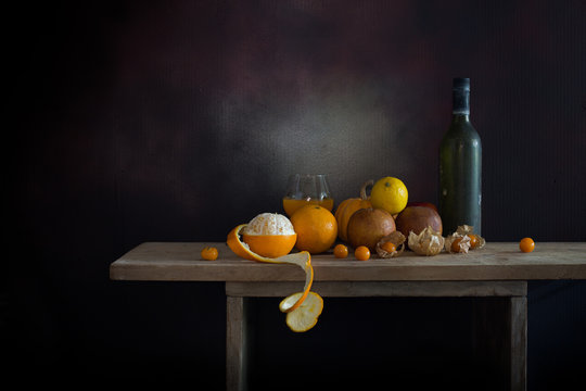 Oranges peel off and other fruits on and old bottle on the plank in dim light night / Still life style  and select focus, space for text..