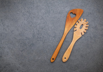 The wooden cooking utensils border. Wooden spoons and wooden spatula on dark stone background with flat lay and copy space.