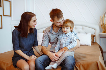 parents with a child playing on bed with toys