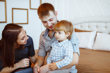 parents with a child playing on bed with toys