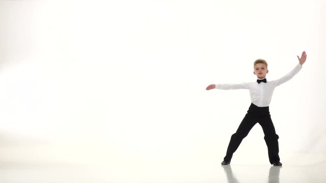 Little boy the dancer spins out gracefully the movements. White background. Slow monion