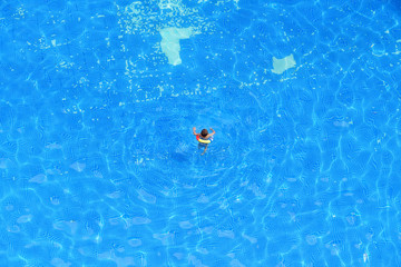 Fototapeta na wymiar Kid with a swim ring playing in the pool.
