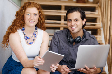 Portrait of two young people sitting at the stairs in office