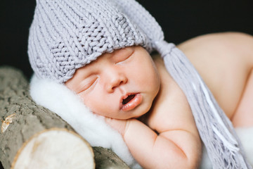 Новорожденный ребенок спит на лежанке из дерева в сиреневой вязаной шапке newborn child sleeps on a stove bench from a tree in a lilac knitted cap © annaperevozkina