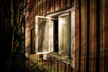 Open dirty window on an empty deserted house against the forest