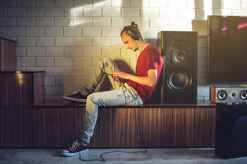 Handsome, a music lover listens to music with headphones with a mobile phone on the media and large speakers.