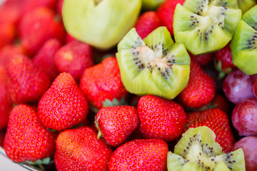 Fresh fruits on plate. Strawberries, kiwi, grapes close up. Selective focus