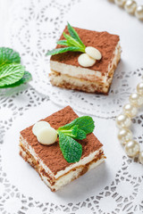 Mini cakes tiramisu with white chocolate, cocoa and candies on light background close up. Delicious dessert