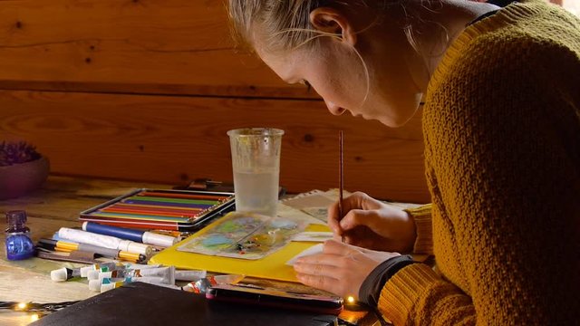 female artist painter woman paiting a watercolor picture of a bear, indoors, cozy wooden cabin
