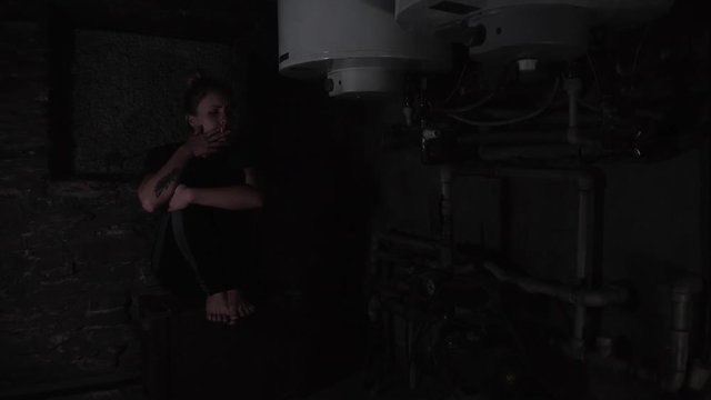depressed anxious woman sitting in a dark corner of a basement, blinking overhead light