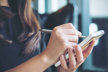 Closeup image of a woman writing and taking note on notebook in office