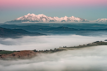 Fototapeta na wymiar Beautiful spring panorama over misty Spisz highland to snowy Tatra mountains in the morning, Poland