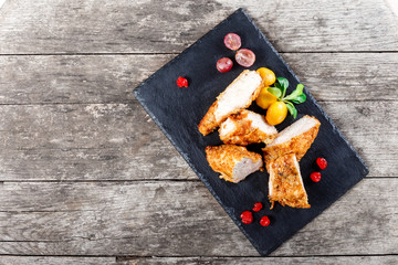 Grilled chicken breasts with vegetables and berries on stone slate background on wooden background close up